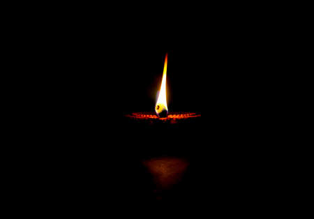 Happy Diwali. Clay diya candle illuminated in Dipavali, Hindu festival of lights. Traditional oil lamp on dark backgroundの写真素材