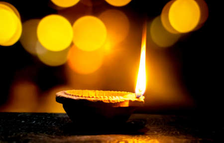 Happy Diwali. Clay diya candle illuminated in Dipavali, Hindu festival of lights. Traditional oil lamp on dark backgroundの写真素材