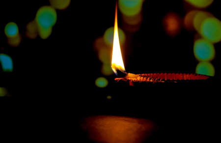 Happy Diwali. Clay diya candle illuminated in Dipavali, Hindu festival of lights. Traditional oil lamp on dark backgroundの写真素材