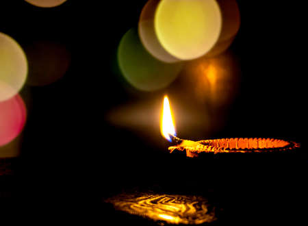 Diwali, Hindu festival of lights. Clay diya candle illuminated in Deepawali. Traditional oil lamp on dark background, copy space.の写真素材