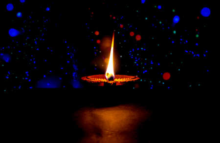 Happy Diwali. Clay diya candle illuminated in Dipavali, Hindu festival of lights. Traditional oil lamp on dark backgroundの写真素材