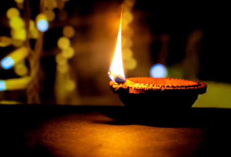 Happy Diwali. Clay diya candle illuminated in Dipavali, Hindu festival of lights. Traditional oil lamp on dark backgroundの写真素材