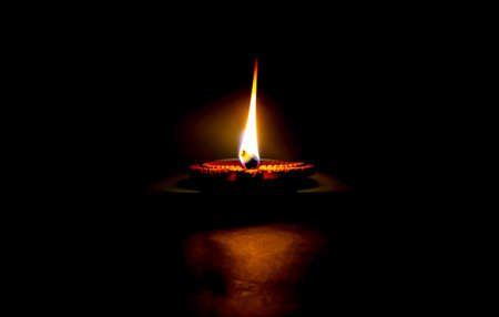 Happy Diwali. Clay diya candle illuminated in Dipavali, Hindu festival of lights. Traditional oil lamp on dark backgroundの写真素材