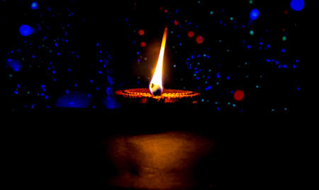 Happy Diwali. Clay diya candle illuminated in Dipavali, Hindu festival of lights. Traditional oil lamp on dark backgroundの写真素材