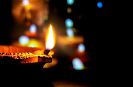 Happy Diwali. Clay diya candle illuminated in Dipavali, Hindu festival of lights. Traditional oil lamp on dark backgroundの写真素材