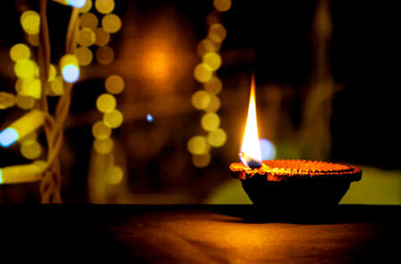 Happy Diwali. Clay diya candle illuminated in Dipavali, Hindu festival of lights. Traditional oil lamp on dark backgroundの写真素材