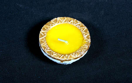 A close-up of a yellow candle on black background.の写真素材