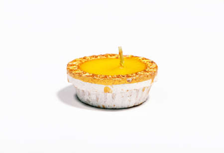 A close-up of a yellow candle on white backgroundの写真素材