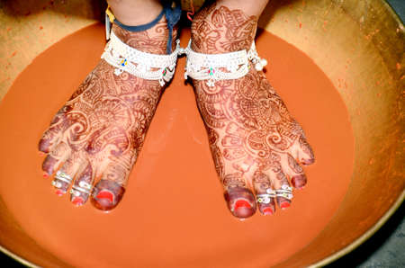 Griha Pravesh Ritual - Right feet of a Newly married Indian Hindu bride in Saree stepping in a plate filled with liquid kumkum before entering house for the first timeの写真素材
