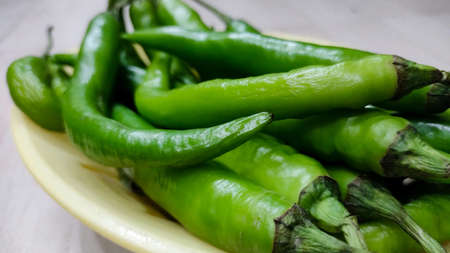 Green peppers in the threshing basket on wooden table in indiaの写真素材