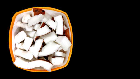 Fresh coconut pieces in a bowl on dark color background with copy space