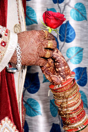 A closeup of an Indian groom giving a rose flower to a bride during wedding ceremonyの写真素材