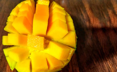 Perfect mango slice cut in cubes. Female hands holding fresh juicy mangoの写真素材