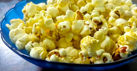 Fresh popcorn in a blue bowl on wooden tableの写真素材