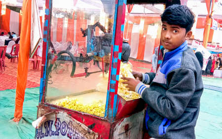 Lucknow, India, January 2021 : A boy selling popcorn with a machine in indiaのeditorial素材