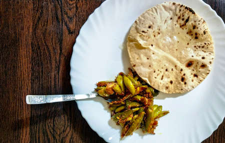Indian Vegetable parwal Curry and Chapati - Homemade chapati (Indian bread) served with Indian parwal curry in a white plate on a wooden tableの写真素材