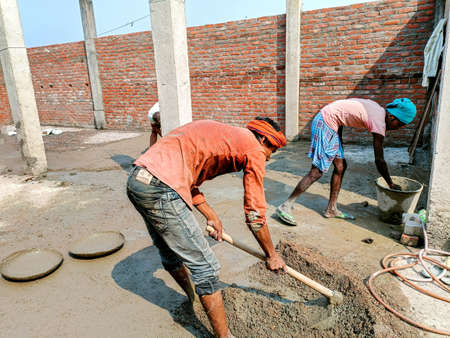 Lucknow, India, October 2021 : Indian workers doing construction work manually on floor using a shovelのeditorial素材