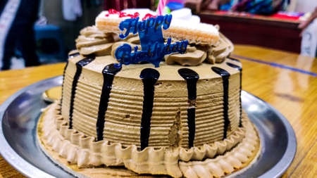 A tasty decorated Birthday Chocolate Cake with Cream and Nuts on the table