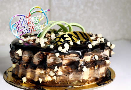 A tasty decorated Birthday Chocolate Cake with Cream and Nuts on the tableの写真素材
