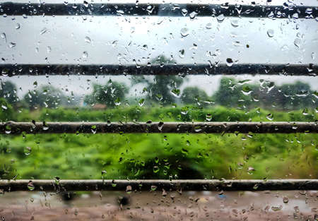 A Closeup image of water droplets on the window of running train during rain