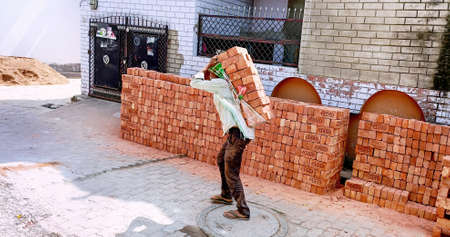 Lucknow, Uttar pradesh, march 2022 : An Indian Worker carrying bricks on their backs at lucknow