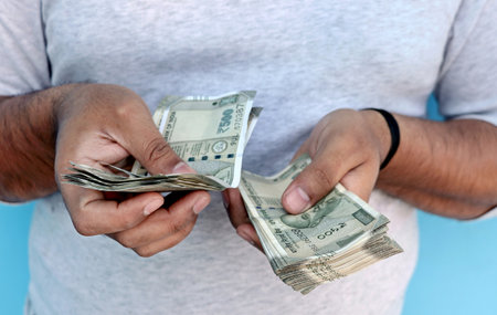 A Man counting 500 rupee banknotes
