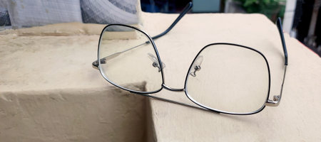 Stylish eye glasses in metal frame on balcony wall. Glasses that correct eyesight from blurred to...