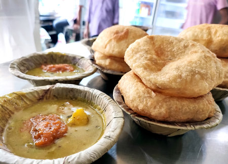 Bedmi puri and potato curry kept in a leaf container (Dona) on the table at the shop of vrindavan