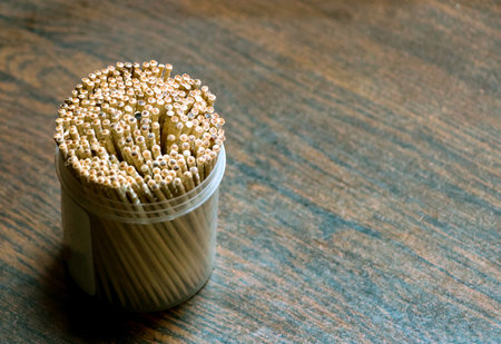 Closeup of toothpicks jar and bunch of toothpicks inside it. Selective focus of toothpicks placed on...