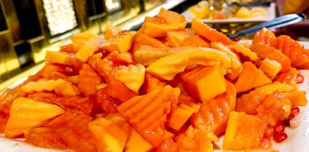 A close-up view of freshly cut ripe papaya served on a buffet counterの写真素材