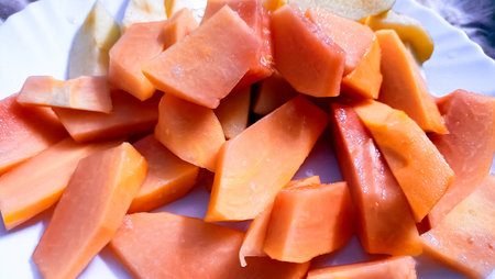 A vibrant close-up of juicy ripe papaya slices arranged on a white plate.の写真素材