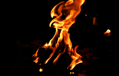 A dramatic close-up view of glowing orange flames rising in the dark, symbolizing warmth, energy,...