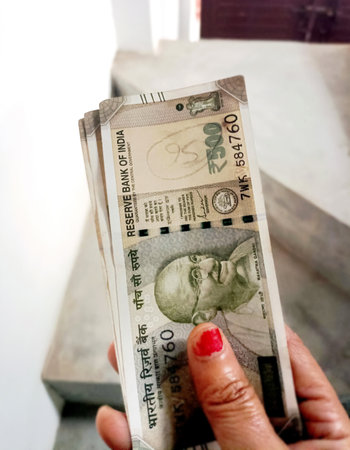 Close-up of a hand holding a thick stack of Indian 500 rupee banknotesの写真素材