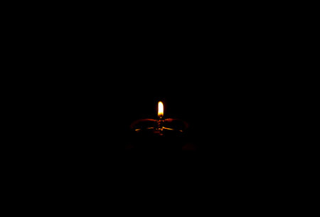 A single clay oil lamp (diya) glowing brightly in the dark, symbolizing light over darkness, hope, and spirituality, often used in Indian festivals like Diwali and traditional rituals.の写真素材