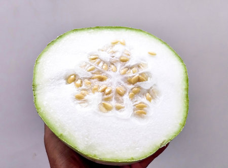 Fresh half-cut kaddu held in hand against a clean white background, suitable for food, vegetable, and cooking concept images.の写真素材