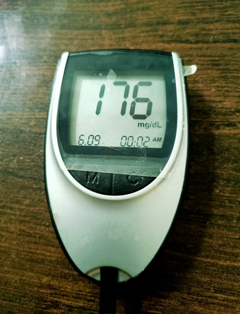 A close up of blood glucose meter with high sugar reading on wooden table in India