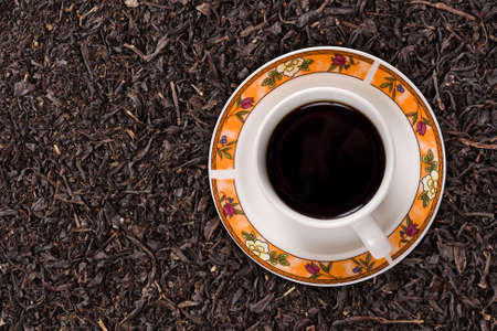 Dried black tea leaves and a cup of black teaの写真素材