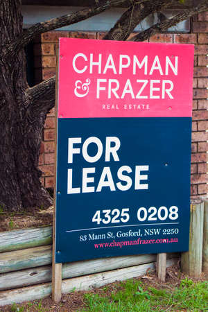 A brightly colored For Lease sign outside a modern brick office building with trees and gardensのeditorial素材