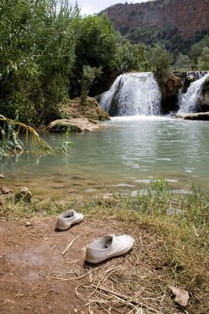 Two shoes sit at the edge of a beautiful pool, someones gone for a cool dipの写真素材