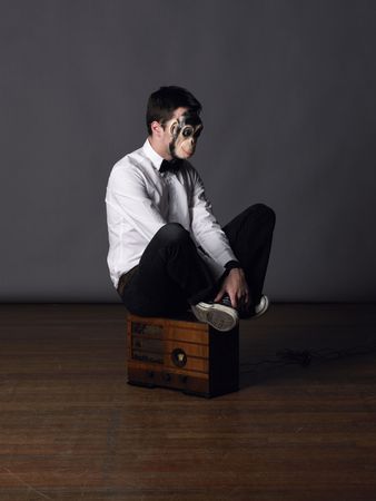 A moan in a monkey mask sits on an old radio