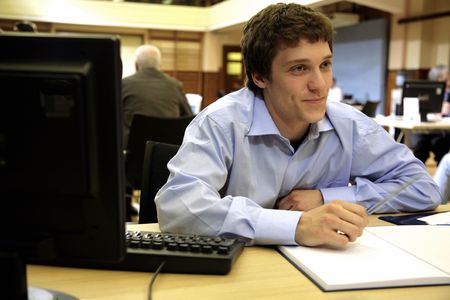 A young worker/Student smiles whilst working on a new projectの写真素材