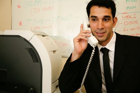 A Man at his desk answers the phoneの写真素材