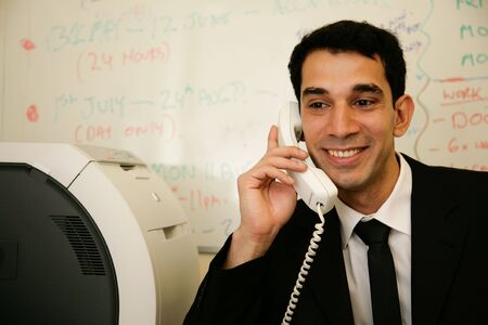 a worker answers the telephone in his officeの写真素材