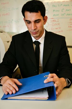 An asian worker looks unhappily at a folder of workの写真素材