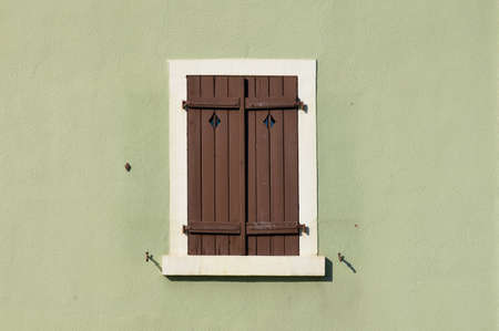 Closed shuttered wooden window on green painted wall in Lahr, Germanyの写真素材
