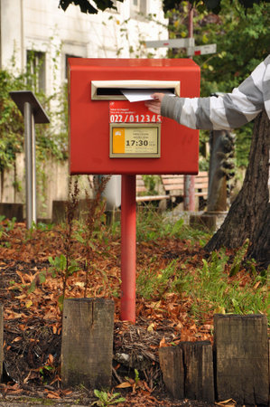 Hand puting a letter in a collection box of Bpost the Belgian national mail delivery companyのeditorial素材