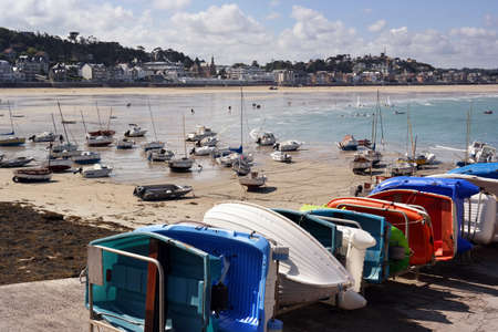 Sailboats at ebb tide on the beach and small rowing boats at the quay of Pleneuf-Val-Andre harbour, Brittany, Franceの写真素材