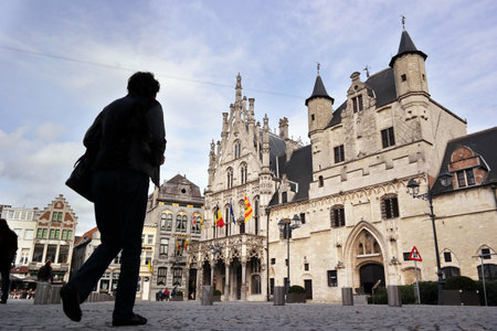 MECHELEN, BELGIUM - OCTOBER 2014: Silhouette walks on the Grote Markt in front of the former cloth hall, the present-day town hallのeditorial素材