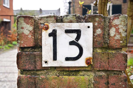 Number 13 sign. House Number Thirteen sign on brick stone wall