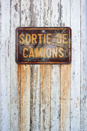 Sortie de Camions - Rusty sign in French with: truck exit, on a white painted wooden panelの写真素材